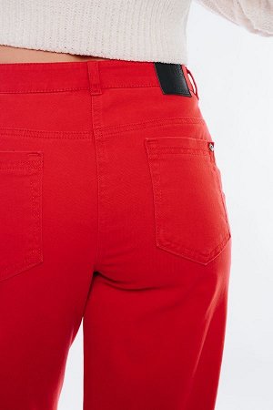 Брюки Молодежные джинсы-бананы сочного красного цвета. Детали: спереди застежка на молнию и пуговицу, боковые карманы с отрезным бочком, по линии пояса защипы, сзади под кокеткой накладные карманы с х