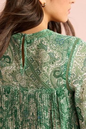 Блузка с длинными рукавами, складками спереди и круглым вырезом.