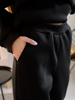 Брюки Описание и параметры
Женские брюки из футера с начесом черного цвета свободного силуэта с боковыми карманами. Пояс на широкой эластичной резинке. Низ отделан манжетами. Изделие выполнено из трик