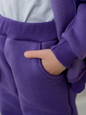 Брюки Описание и параметры
Зауженные утепленные модные брюки из футера с начесом фиолетового цвета для девочки. С боковыми карманами и манжетами снизу. Изделие выполнено из трикотажа премиального каче
